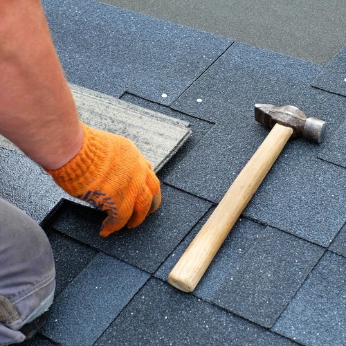 close-up of a roofer repairing a shingle roof