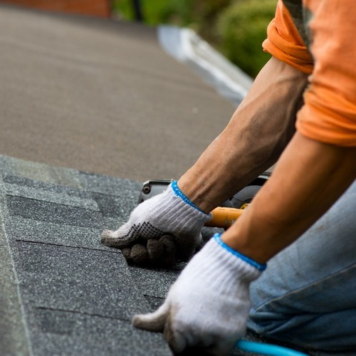 close-up of a roofer laying down shingles