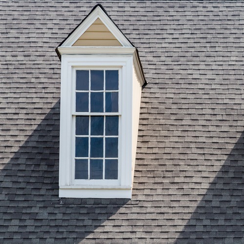 a white dormer and windows on a brown shingle roof