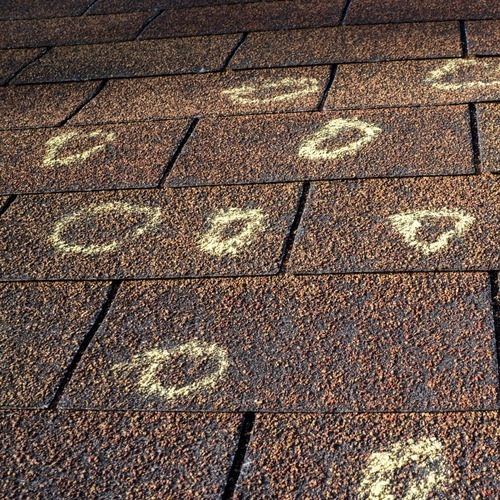 damaged spots marked on an asphalt shingle roof